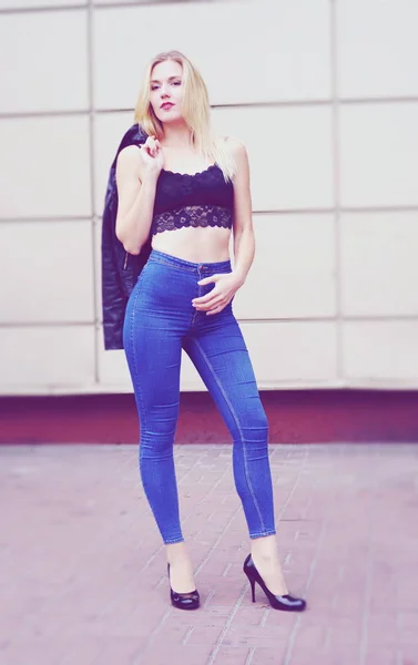 Hermosa chica posando en pantalones vaqueros azules y top negro —  Fotos de Stock