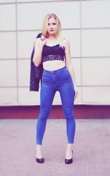 Vacker flicka poserar i blå jeans och svart gröda topp — Stockfoto