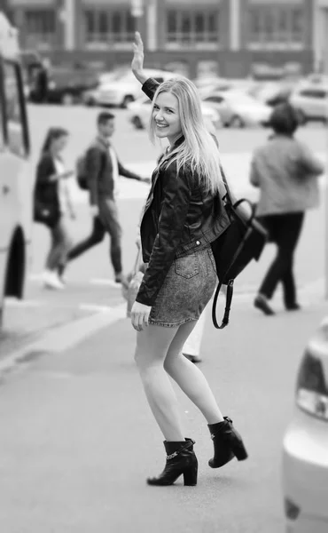 Hermosa chica sonriendo y diciendo adiós en una calle — Foto de Stock