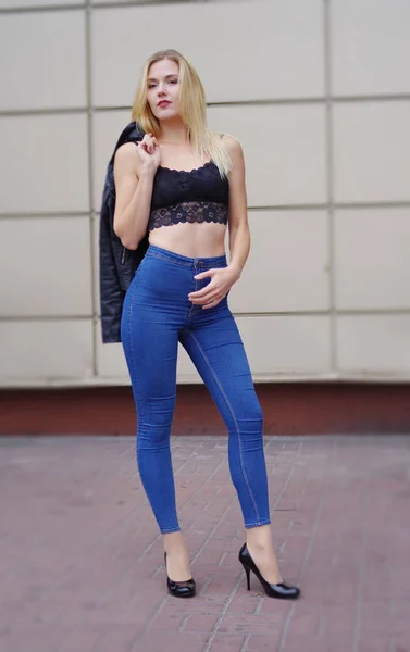 Krásná dívka pózuje v modré džíny a černé tílko — Stock fotografie