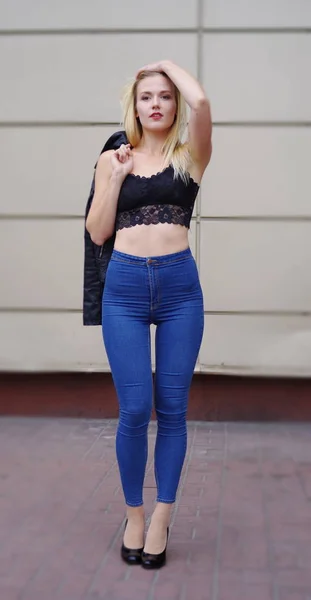 Sexy chica bonita posando en pantalones vaqueros azules y top negro —  Fotos de Stock