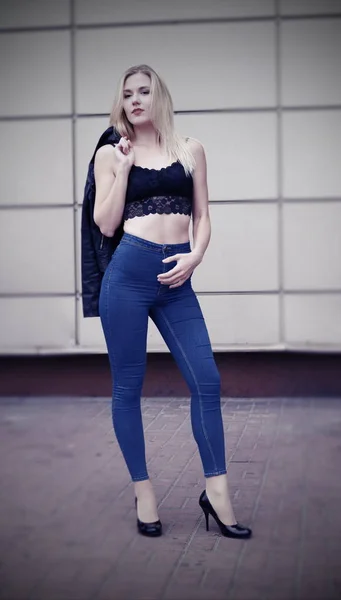 Красивая девушка позирует в синих джинсах и черном топе — стоковое фото