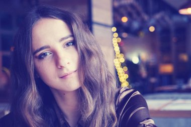 Uzun kahverengi saçlı ve ışık patlamaları bir kafede yalnız şirin kız