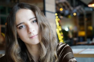 Uzun kahverengi saçlı ve ışık patlamaları bir kafede yalnız şirin kız