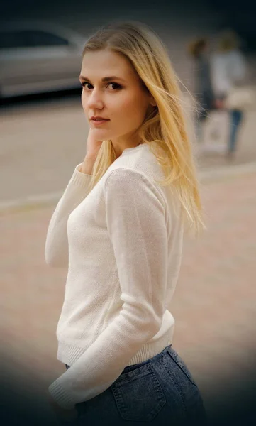 Hezká mladá žena v bílém svetru pózuje v ulici — Stock fotografie