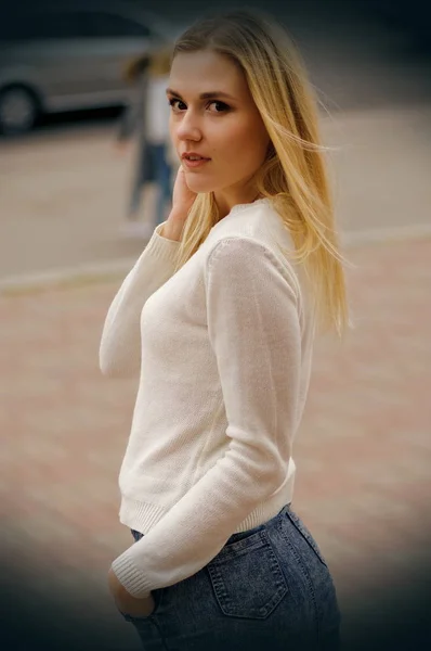 Dość młoda dziewczyna w białym swetrze pozowanie przy ulicy — Zdjęcie stockowe
