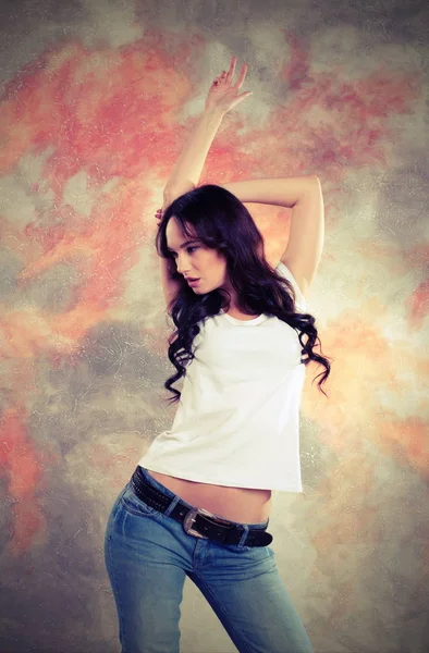Portret van een mooie brunette vrouw in jeans en een witte T-shirt. — Stockfoto