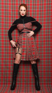 Kırmızı kareli elbiseli, makaslı kızıl saçlı kız.