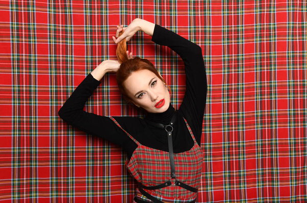 Рыжая девушка тянет себя за хвост
