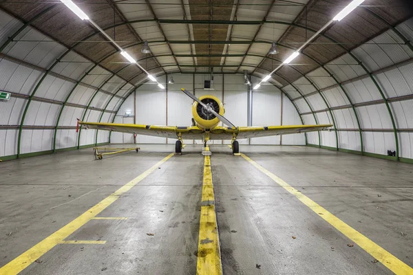 Vintage old yellow war plane inside of a empty hangar
