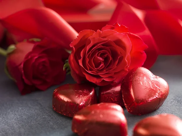 Hart shaped chocolate with valentine 's day roses and red ribbon — стоковое фото