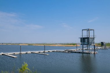 Mavi gökyüzünün altında kürek çekmek için suya giden bir patika.