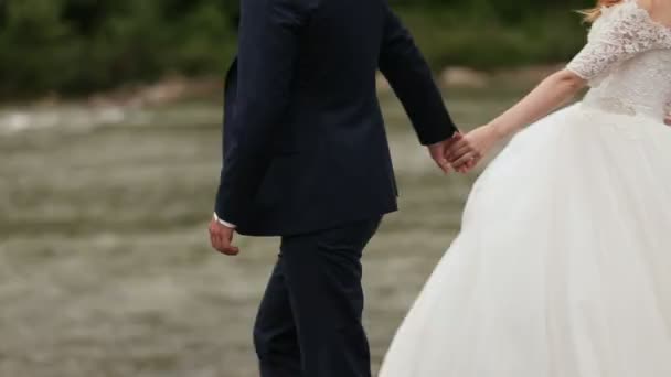 Bride and groom holding hands near the river — Stock Video