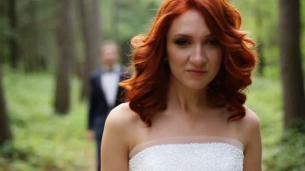 Rothaarige lockige Braut und Bräutigam hinter ihr — Stockvideo