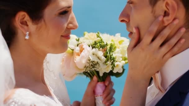 Abraço casado em um contexto o mar com um buquê de casamento — Vídeo de Stock