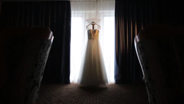 Свадебное платье висит перед окном — стоковое видео