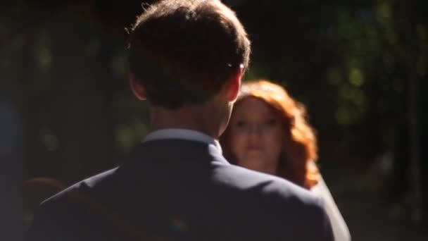 Mariée et marié s'embrassent dans une allée ensoleillée du parc .