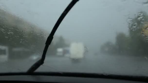 Tráfico lluvioso. Mirando a través del parabrisas en el tráfico desenfocado. lluvia fuerte cayendo y limpiaparabrisas chirriantes . — Vídeo de stock