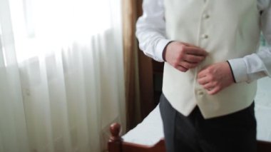 Genç gelin elbise ve gömlek düğmeleri. Mutlu genç damat onların düğün günü. Adam bir pencerenin önünde tişörtünü kadar düğmelerini. Düğün kavramı.