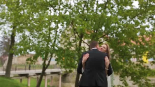 Hermosa novia feliz y novio posando cerca del árbol verde en el parque — Vídeos de Stock