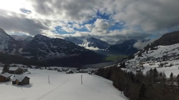 Vuelo sobre el pueblo cubierto de nieve en las montañas — Vídeos de Stock