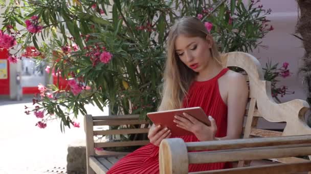 Hermosa mujer joven con una tableta PC. La chica usa una tableta como libro — Vídeos de Stock