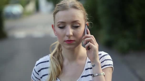 Attraktive junge Frau, die an einem sonnigen Tag glücklich mit ihrem Handy geht und spricht, — Stockvideo