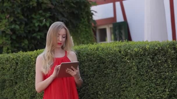 Mulher bonita com um PC tablet. A menina usa um tablet como livro — Vídeo de Stock
