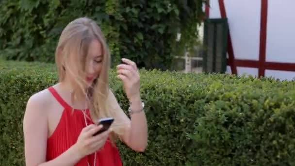Ung flicka lyssna på musik på din telefon via app — Stockvideo