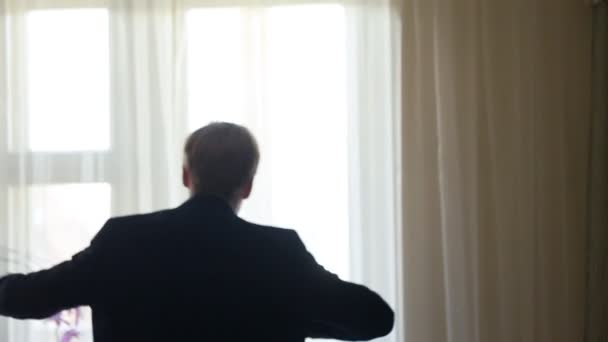 Жених носит куртку у окна — стоковое видео