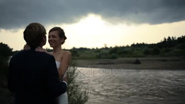 Bruid en bruidegom in liefde op het veld in de buurt van de rivier — Stockvideo