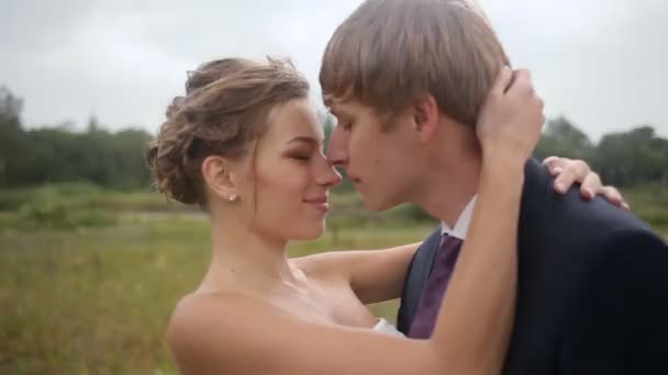 Bruid en bruidegom kussen op het veld — Stockvideo