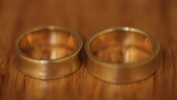 Dva zlaté prsteny na hnědé pozadí — Stock video