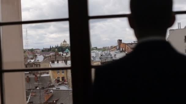 Силуэт мужчины носит куртку, стоящую у окна — стоковое видео