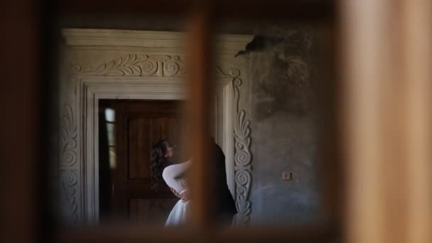 Noivo gentilmente abraça a noiva em um fundo de portas — Vídeo de Stock