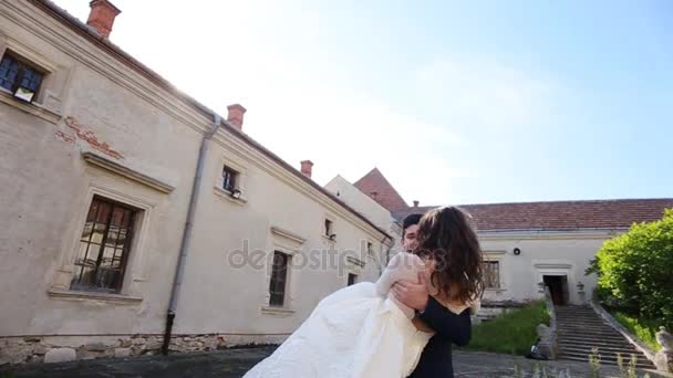 Утішний наречений бере наречену на руки і викручує свій раунд на вулицях старого замку — стокове відео