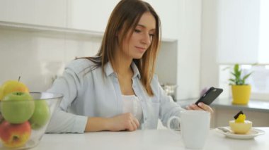 Onun smartphone vasıl izliyor ve kaydırma ve kahve içme kadın.