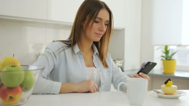 Vrouw op haar smartphone kijken, scrollen en koffie drinken. — Stockvideo