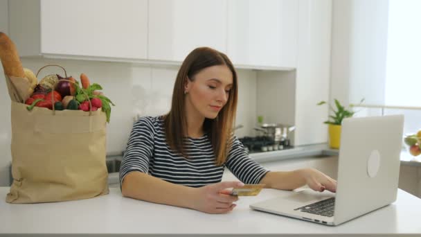 Frau kauft mit Laptop ein und bezahlt online mit Kreditkarte — Stockvideo