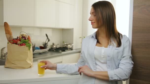 Menina bonita bebendo suco de laranja fresco pela manhã na cozinha . — Vídeo de Stock