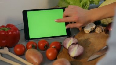 Genç kadın onun tablet mutfakta yemek tarifleri ile kaydırma