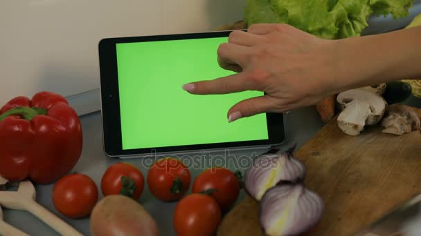 Молодая женщина прокручивает рецепты на планшете на кухне — стоковое видео