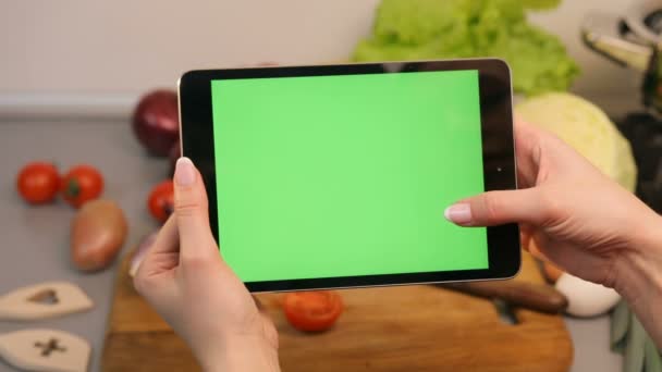 Una donna spara al suo tablet in cucina. Le verdure sono sullo sfondo . — Video Stock