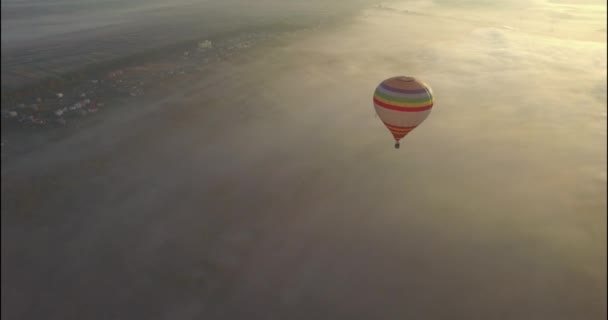 Şehrin yukarısındaki gündoğumu üzerinde saf mavi gökyüzünde yüzen sıcak hava balonu — Stok video