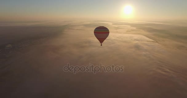 Luftaufnahme eines Heißluftballons, der im strahlend blauen Himmel am Sonnenaufgang schwebt — Stockvideo