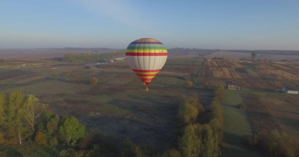 Barevný horkovzdušný balón unášení nad loukami, letecký pohled — Stock video