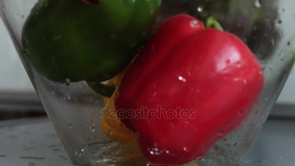 Vista de cerca de la mano poniendo pimienta madura fresca lavada dentro del tazón — Vídeos de Stock