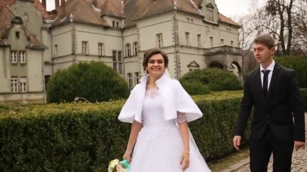 Pareja de boda caminando por el sendero y besándose cerca del hermoso castillo viejo — Vídeos de Stock