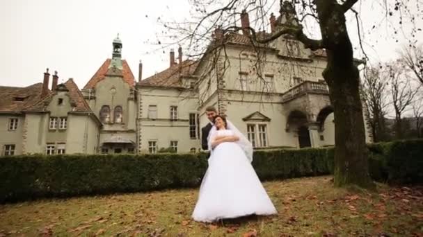 Braut und Bräutigam beim Spaziergang auf dem Laub in der Nähe des alten Schlosses. — Stockvideo
