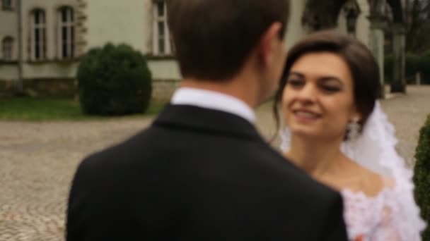 Feliz novia sonriente abrazando novio en el parque cerca del antiguo castillo antiguo . — Vídeos de Stock